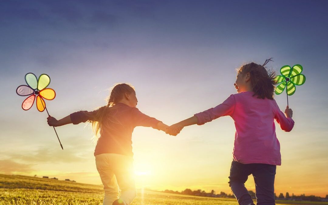 children running through field with pinwheels